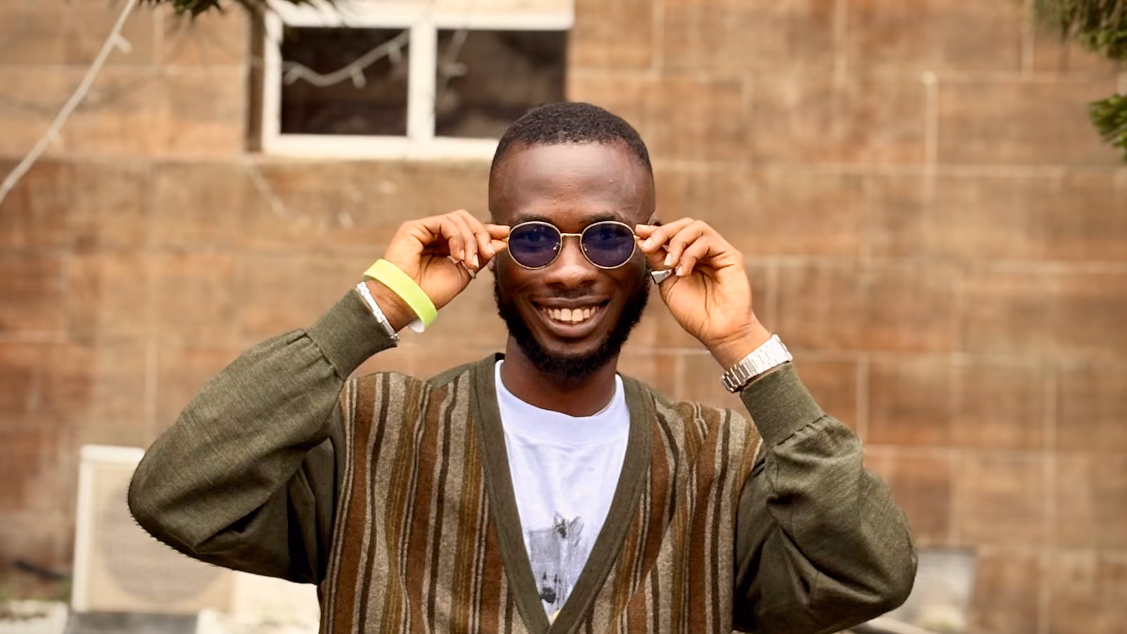 Marvellous smiling and adjusting a pair of round sunglasses